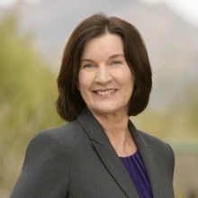 Portrait of Terry Badger, a white woman with shoulder-length dark hair, wearing a blazer and black blouse