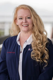 Portrait of a middle-aged woman with long blonde hair smiling. 