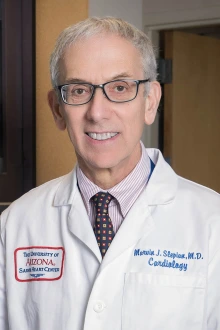 Portrait of Marvin Slepian, an older white man in a white lab coat in a lab setting. 