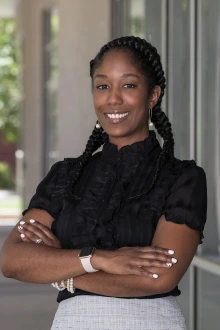 Portrait of Kelly Palmer standing outside smiling with her arms crossed.