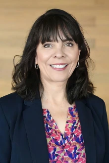 Portrait of a smiling middle-aged white woman with long dark hair. 