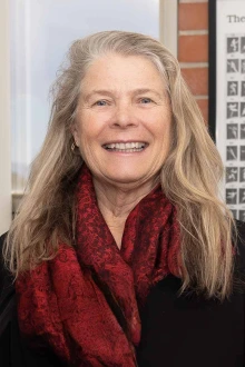 Portrait of Ruth Taylor-Piliae wearing a neck scarf and smiling.