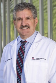 Portrait of man wearing a blue dress shirt and stripped blue and red tie standing outside of a building.