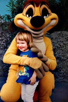 A child being hugged by a theme park mascot 