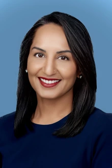 Portrait of a smiling, light-brown skinned woman with long dark hair. 